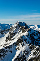 View of the outstanding peak in the High Tatras located on the Polish-Slovak border - Swinica (Svinica ). Tourists and mountaineers visible on the tops. Winter landscape.
