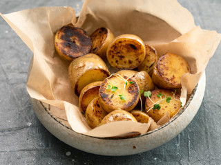 Roasted baby potatoes and microgreen in craft plate on gray background. Baby potato half, roasted.