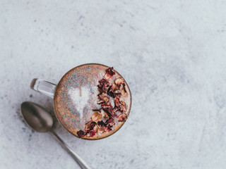 Trendy Coffee with edible glitter and dried rose petals. Cup of sparkly coffee or diamond cappuccino on gray table. Copy space for text. Top view or flat lay.