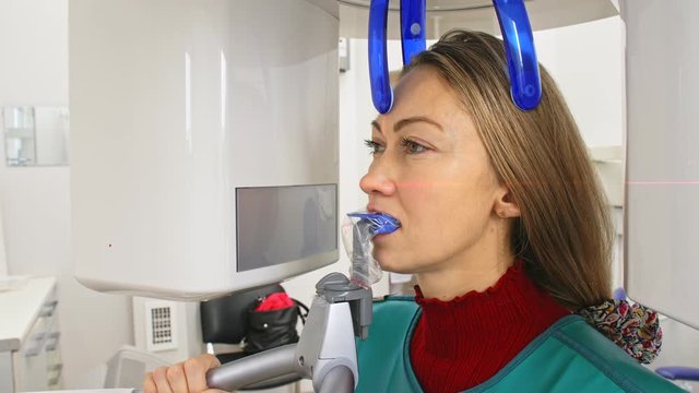 Doctor to take a image 3d scanner tomography of teeth and jaw in modern laboratory dental clinic. Female nurse shows the patient woman an x-ray machine 3d digital scanner. Computer dental diagnostics.