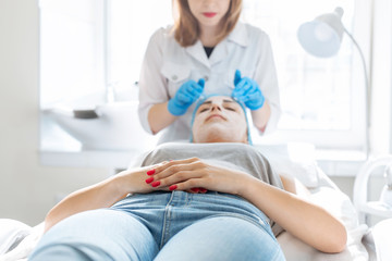 Woman professional doctor beautician applies a mask on a patient's face for skin care. Cosmetic procedures for skin rejuvenation and nutrition