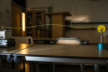 Demonstration of standing waves on a string, illuminated by stroboscope. Science experiment.