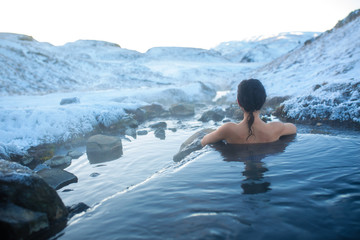 The girl bathes in a hot spring in the open air with a gorgeous view of the snowy mountains....