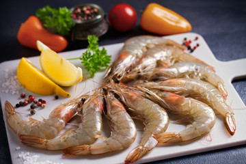 Fresh raw prawn shrimps with ingredients for cooking on chopping board. Seafood