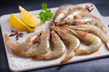 Fresh raw prawn shrimps with ingredients for cooking on chopping board. Seafood