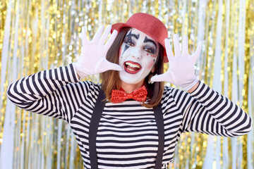 girl dressed in mime with red hat, red bow tie, striped shirt and white gloves.