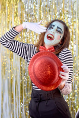 girl dressed in mime with red hat, red bow tie, striped shirt and white gloves.