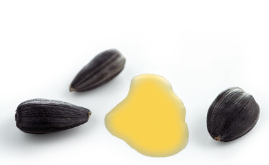 Several sunflower seeds and a puddle of sunflower oil. Selective focus.