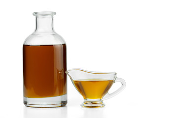 Vegetable oil in a glass bottle and gravy boat. Isolated on a white background.