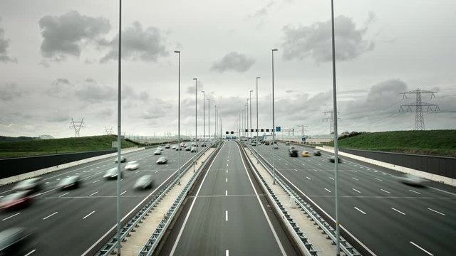 Time-lapse of highway traffic on a grey gloomy day. Wide highway road with five lanes in each direction and two reversible lanes in the middle, connecting Amsterdam and the east of the Netherlands