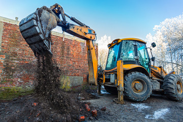 The modern excavator performs excavation work on the construction site. Front view of a digger...