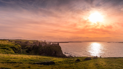 Ruined medieval Dunluce Castle on the cliff at amazing sunset, Wild Atlantic Way, Bushmills, County Antrim, Northern Ireland. Filming location of popular TV show, Game of Thrones, Castle Greyjoy