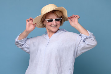 Elegant positive woman in summer hat and pink glasses holding smiling posing to the camera ready for vacation. Studio shot © Viktor Koldunov