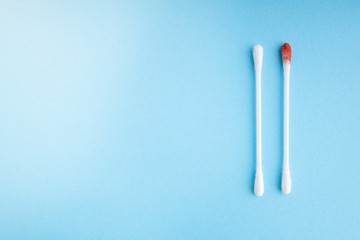 Blood on the hygiene cotton stick. Skincare mockup for design. Menstruation. Stack of disposable cotton stick on a blue background. Cosmetology concept. Bloody wound. Injury. ..