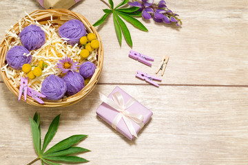 Purple flowers as a present on the table. Violet gift wrapped in paper and pins. Chamomiles, yellow and green plants