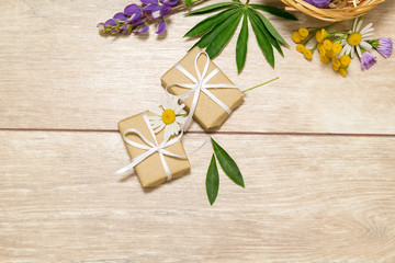 Flat lay of flowers, petals, leaves and gifts. Holiday yellow, purple and white decor on the wooden table. 
