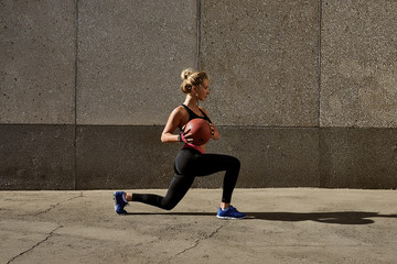 Fitness woman working out at outdoors gym using medicine ball. Sportswoman stretching outdoors with medicine ball. Copyspace for text