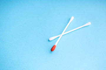 Blood on the hygiene cotton stick. Skincare mockup for design. Menstruation. Stack of disposable cotton stick on a blue background. Cosmetology concept. Bloody wound. Injury. ..