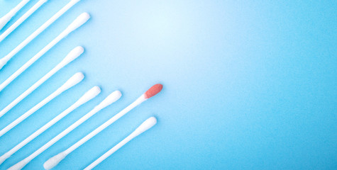Blood on the hygiene cotton stick. Skincare mockup for design. Menstruation. Stack of disposable cotton stick on a blue background. Cosmetology concept. Bloody wound. Injury. ..