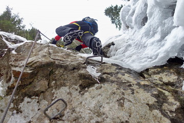 Man climbing snowy via ferrata on winter time. Walking on glacier with ice crampons. Extreme sport and Winter Hiking concept.