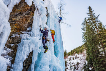 Ice Climbing Man with an Ice Axe and Crampons on a Frozen Waterfall