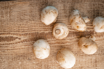 Bunch of fresh champignon mushrooms on the wooden background. Close up of vegetarian healthy food.