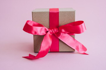 A gift box made of eco-friendly material and decorated with a pink bow of satin ribbon. Kraft box for surprise on Valentine's Day, March 8, Mother's Day.