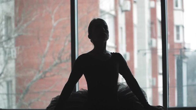 Silhouette of a ballerina on a background of the city a beautifully moving dance. In a black tutu and Pointe shoes. The image of the black Swan from the ballet. Slow motion