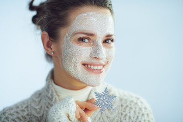 smiling elegant woman with white facial mask showing snowflake