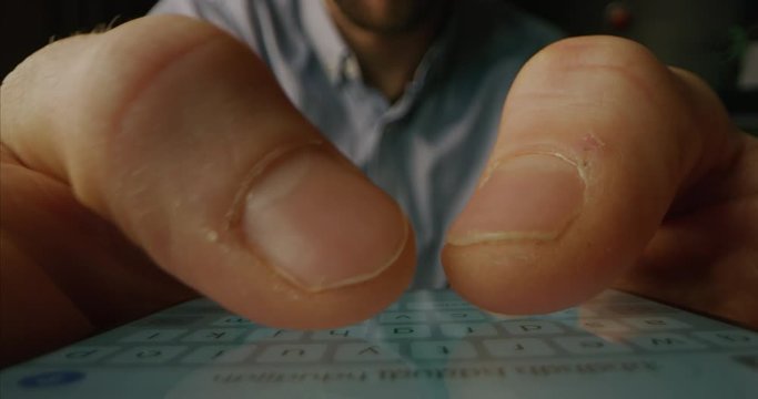 Alternative macro close up of an young businessman hands using a touchscreen touchpad keyboard of an anonymous smartphone for texting messages and navigating on web.