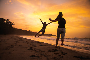 Couple jumping on the beach with sunset nature background