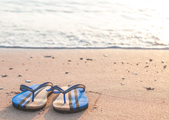 Beautiful beach flip flops on the beach under the wave, on a blurred background, closeup.