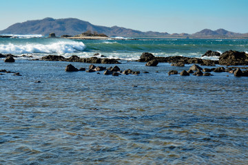 Wave breaking in ocean, Costa RIca vista with mountains in background and beautiful water, rocks