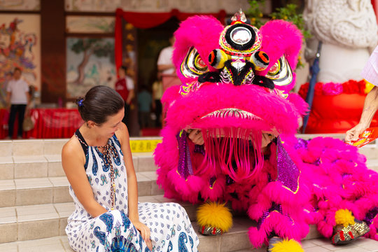 A European tourist girl at a Chinese New Year celebration in a Chinese temple is photographed with a traditional Chinese dragon. Festive Chinese entertainment