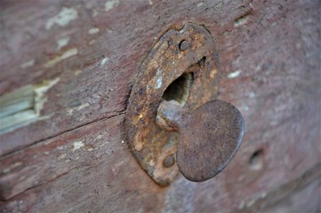 close up of a rusty bolt. Weathered wooden brown detail of door and lock.