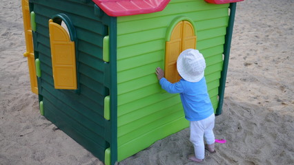 Dziecko w kapelusiku przy domku dziecięcym do zabawy na plaży © Marcin