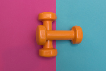 Two dumbbells for sport on the pink blue background.