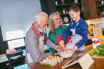 Young boy having fun with her grandparents in the kitchen