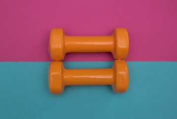 Two dumbbells for sport on the pink blue background.