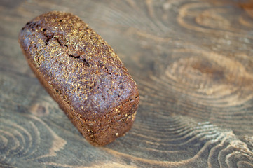 Fototapeta premium a loaf of black bread on a wooden background, the concept of rising bread prices