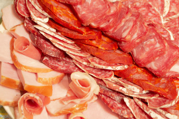Antipasti composition of italian cured meat types. Salami, ham and dry sausage slices, closeup. Food background, texture and wallpaper