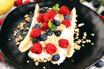 Sweet Homemade Banana Split with yogurt, granola, berries and mint. Banana Split with healthy ingredients