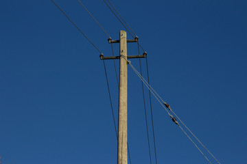 Wooden power pole and power lines in front of clear blue sky