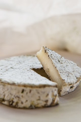 Handmade brie cheese in herbs on wooden table