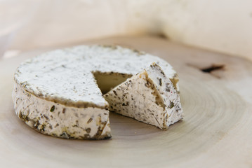Handmade brie cheese in herbs on wooden table