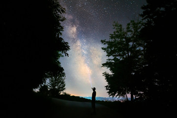 silhouette of man and trees under milky way