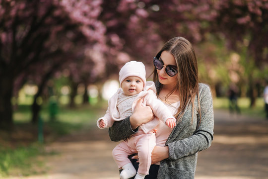 Portrait of mother and her little baby girl. Beautiful mom and cute baby. Mother hud her daughter. Baby dressed in peanch colour hat and smile