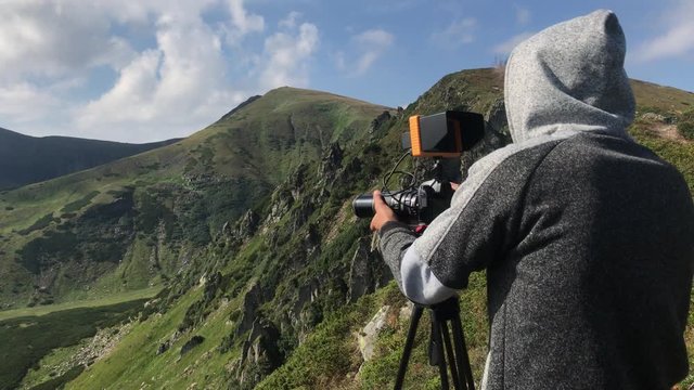 Backview cameraman filming beautiful landscape of mountains. Backstage.
