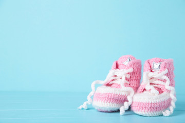 Pink baby booties on blue background with copy space