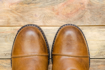 Rounded nose of men's brown shoes on a wooden background close-up with a copy of the space. view top